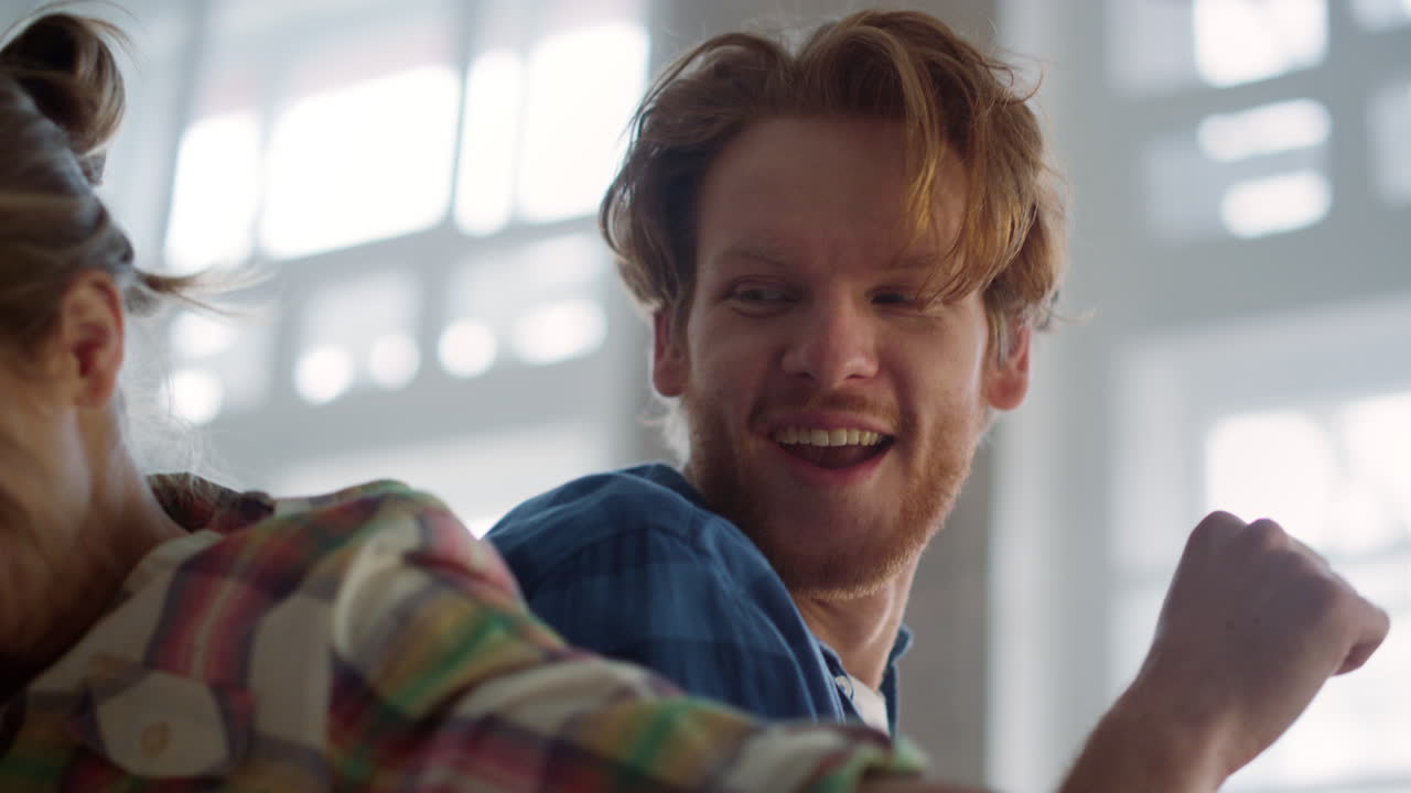 미소 짓는 커플이 실내에서 손을 들고 가족이 집 수리 끝을 축하하고 있습니다.