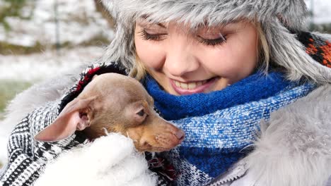 mujer jugando con su pequeño perro fuera del invierno