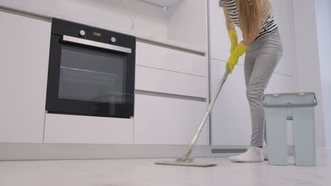 a happy young woman cleans the house she wipes the floor with a mop