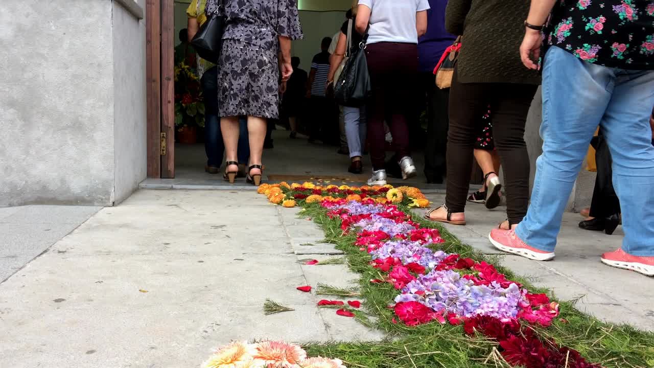 procesión religiosa cristiana, cuerpo organizado cristiano de personas que avanzan de manera formal o ceremonial, el piso está decorado con flores frescas que conducen a la iglesia