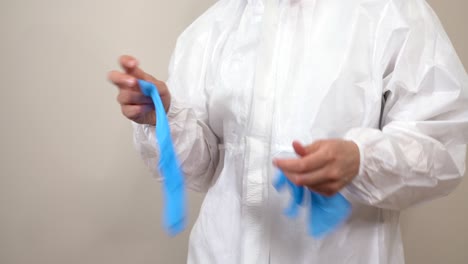 worker in ppe suit taking off latex gloves