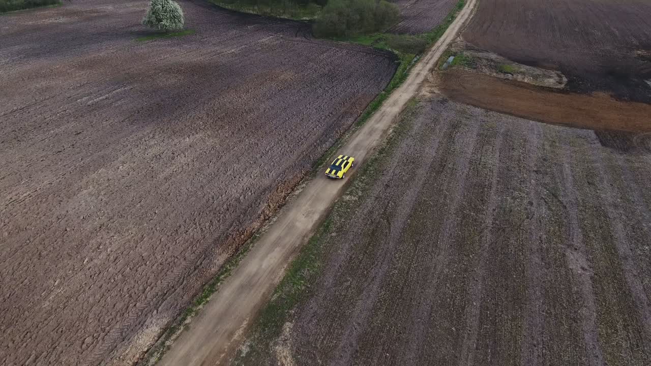 Yellow With Black Stripes Classic Ford Consul Rides On A Gravel Road. 4K Aerial Active-Track Footage