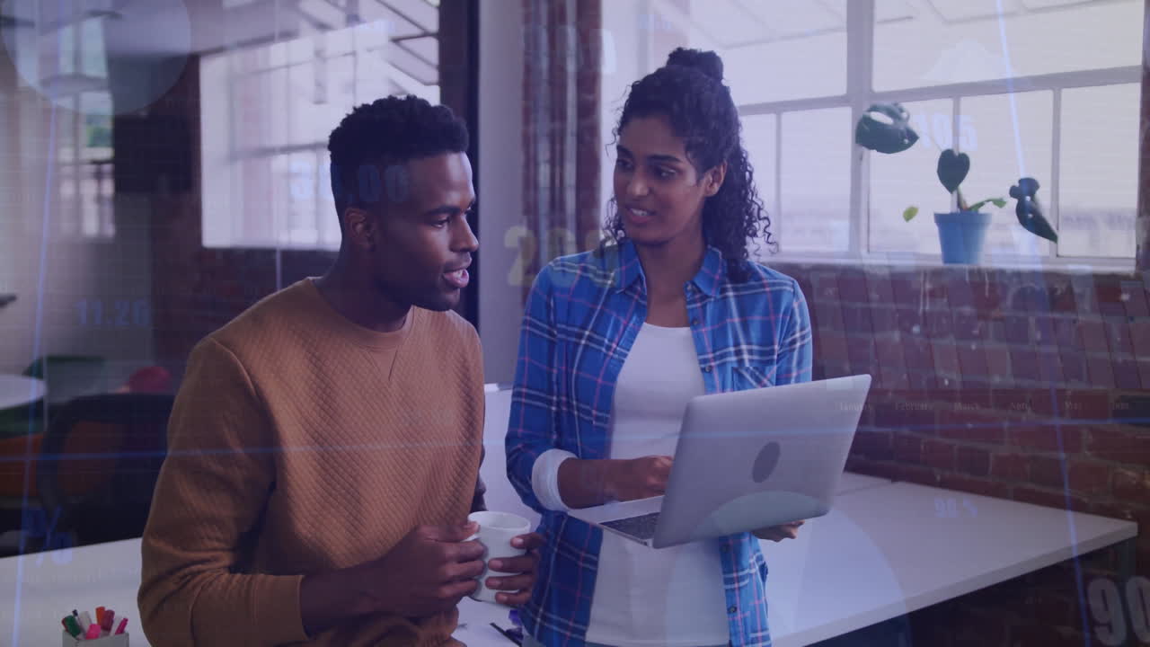 Discussing work, two people holding laptop and coffee in modern office