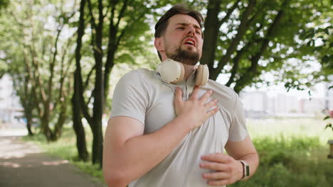sports man runner jogger having heart attack or chest pain after running workout in urban city park