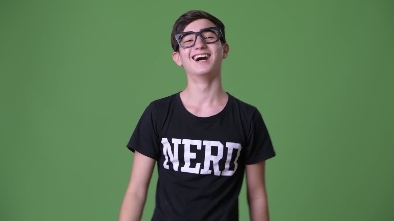 Young handsome Iranian teenage boy against green background