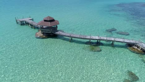 Drone-shot-of-wooden-footbridge-leading-into-the-sea