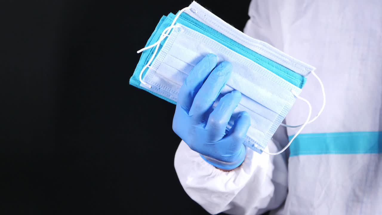 trabajador médico sosteniendo una pila de máscaras faciales y usando guantes azules