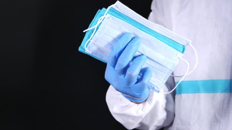 medical worker holding a stack of face masks and wearing blue gloves