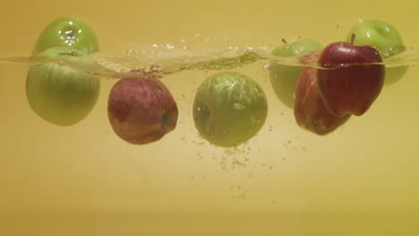 Shot-of-a-bunch-of-red-and-green-apples-dropped-in-water