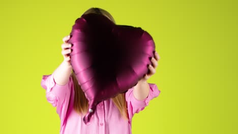 Hübsche-Blonde-Frau,-Die-Einen-Herzförmigen-Lila-Ballon-Umarmt,-Valentinsstimmung-Mit-Buntem-Hintergrund,-Studioaufnahme