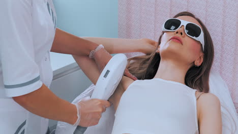 cosmetologist does laser hair removal of armpits of patient. epilation procedure. cosmetologist does laser hair removal of the armpits of the patient. epilation