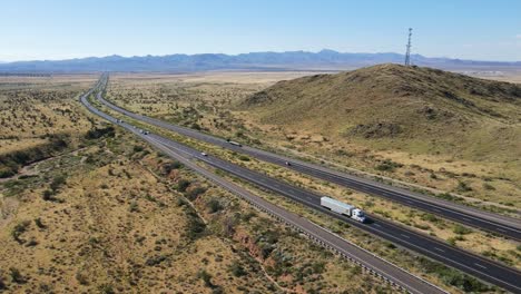 aerial view, cars trucks, semis driving on highway, mountains and cell tower in background