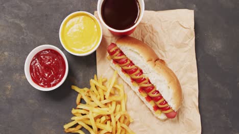 Video-of-hot-dog-with-mustard,-ketchup-and-chips-on-a-black-surface