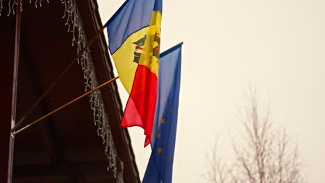 Blick-Nach-Oben-In-Die-Flaggen-Der-Republik-Moldau-Und-Europas,-Die-Im-Freien-An-Der-Hausdecke-Hängen