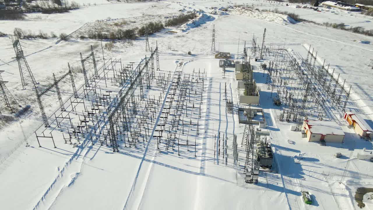 Aerial orbit of high voltage electrical substation with transformers, battery storage and rooftop cooling systems operating in bright winter conditions