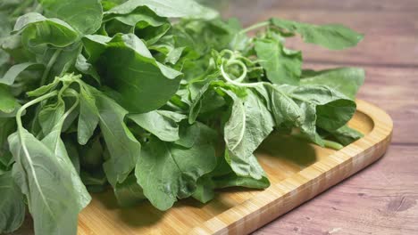 fresh green leafy vegetables on wooden tray