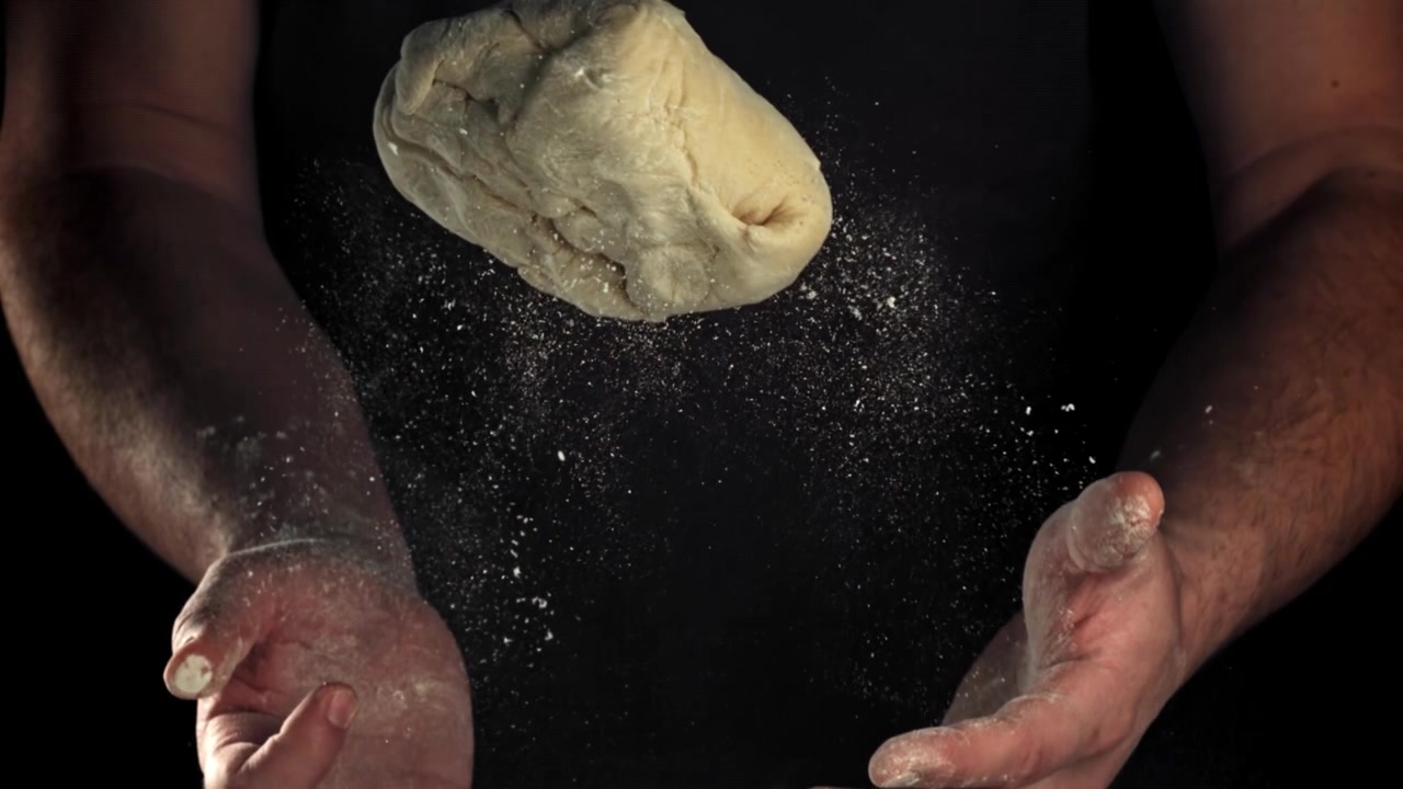 Slow Motion of Hands Tossing Dough with Flour