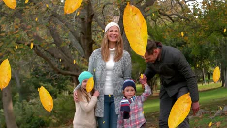 animation of fall leaves falling over happy caucasian family in autumn park