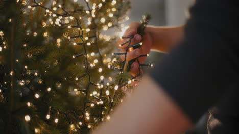 uomo con luci a led luminose che decorano l'albero di natale