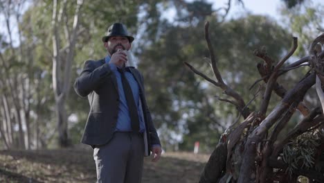 man police detective in jacket and hat outside drinking alcohol flask investigating scene