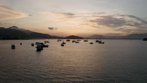 aerial view of yachts, boats and sailboats anchored near a brazilian coast at a beautiful sunset