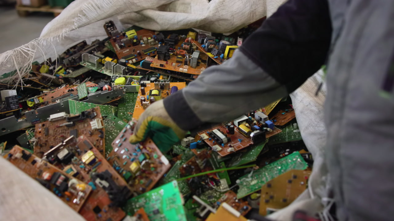 Gloved Worker Hands Sorting Circuit Boards Inside Recycling Workshop, Closeup Of Manual Inspection. Creative