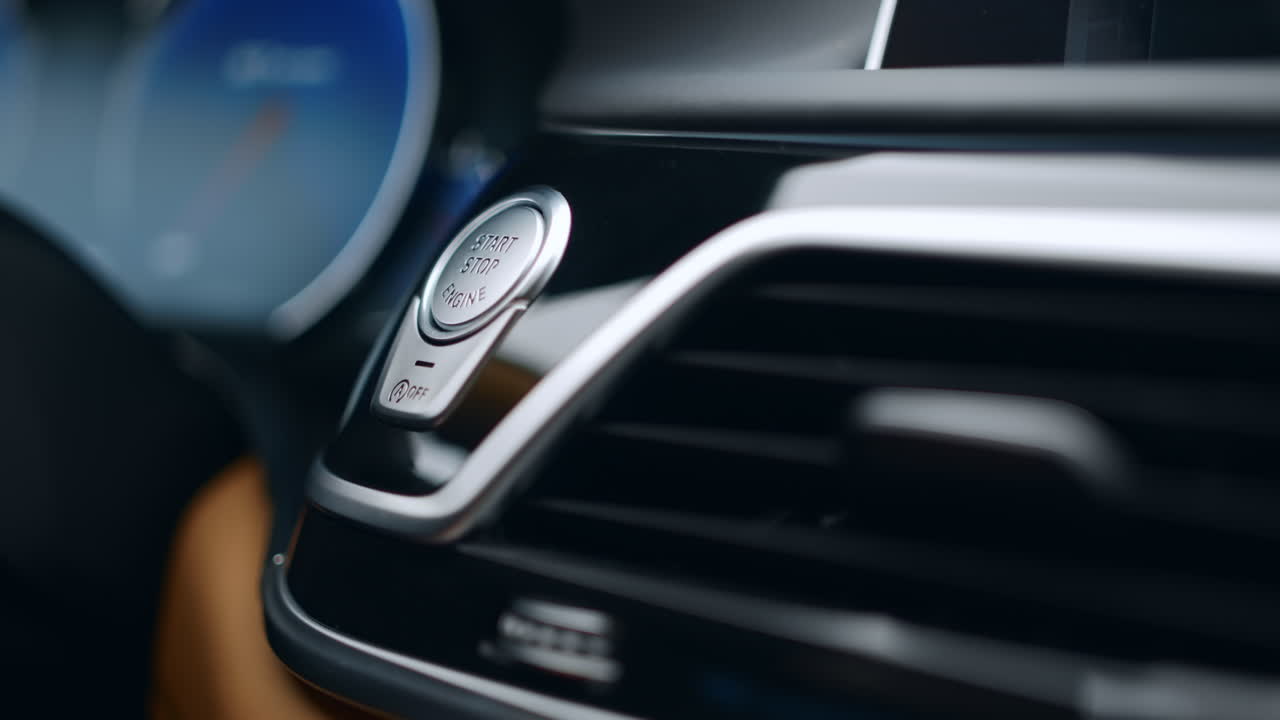 человек нажимает на кнопку запуска двигателя в машине