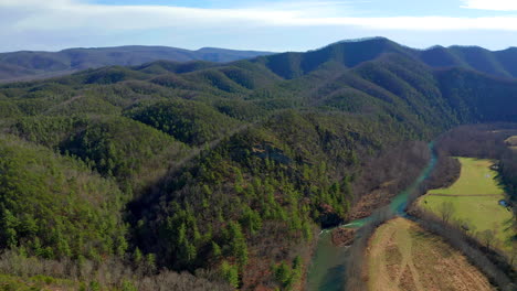 drone shot of river valley over mountains and rockface cliffs into forest