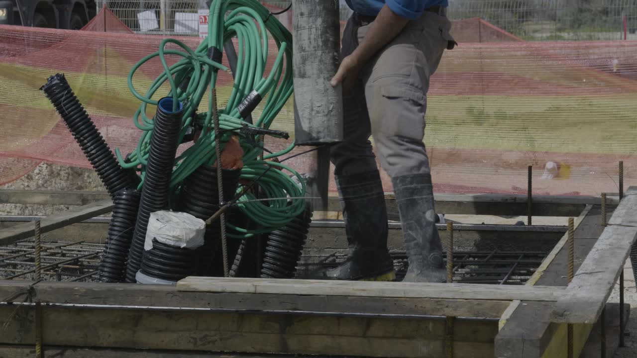 Close-up of a worker pouring concrete on a slab with metal bars, seen from the waist down on a construction site - Israel