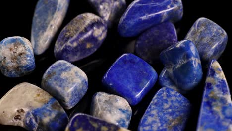 Lapis lazuli stones rotate under bright lighting, showcasing their vibrant blue hues and natural patterns