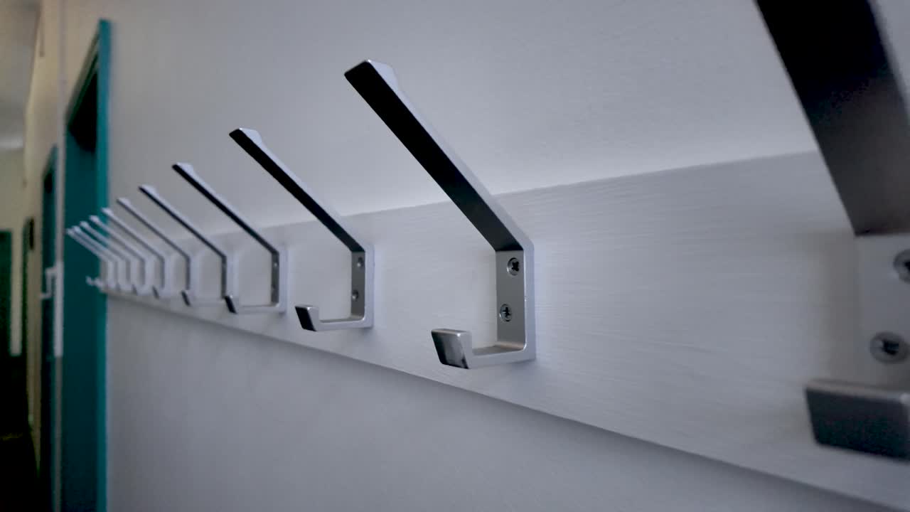 Row of Metal Coat Hooks Mounted on White Wall in Corridor Featuring Modern Design and Practical Storage Solutions for Entryways and Public Spaces