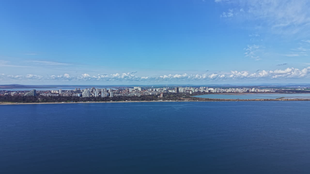 View of a coastal city from above during daytime near the ocean with clear blue skies and clouds