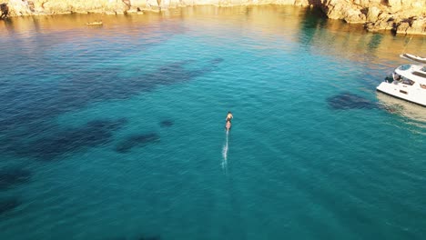 Vista-Aérea-De-Un-Hombre-Usando-Una-Tabla-De-Surf-Eléctrica-En-Las-Aguas-Turquesas-De-La-Costa-De-Cala-Escondida