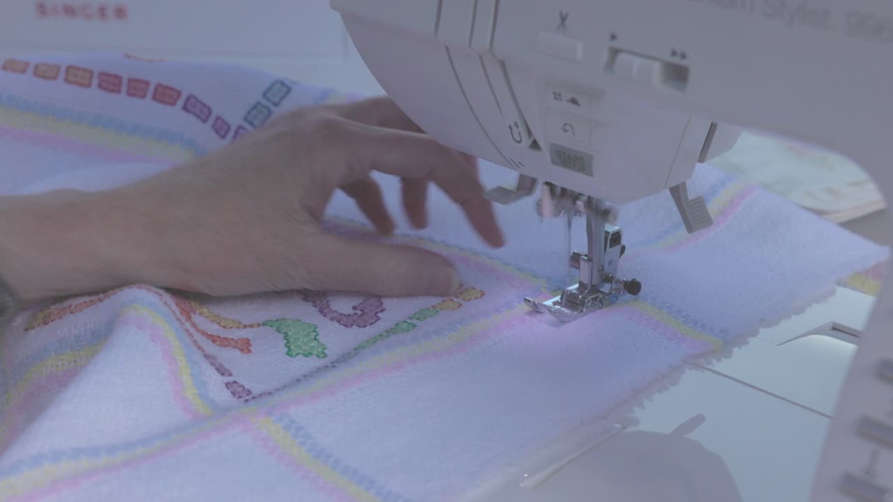 electric sewing machine putting complex stitches around the border of a baby blanket