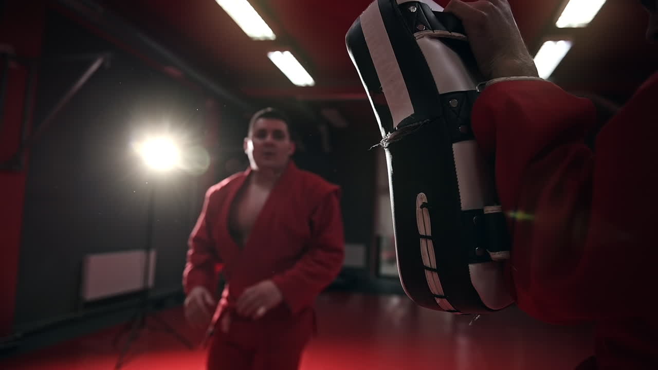 Taekwondo practitioner in a red kimono is training in a gym. Slow motion
