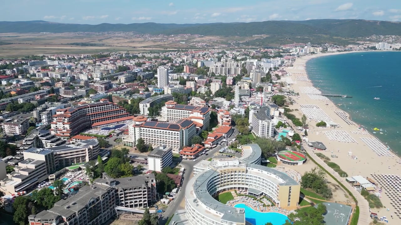 Drone, Sunny Beach sahil şeridinin üzerinde ileri doğru uçarak Bulgaristan'daki Karadeniz boyunca uzanan uzun kumlu plajı, otelleri ve deniz kenarı gezinti yolunu gözler önüne seriyor.