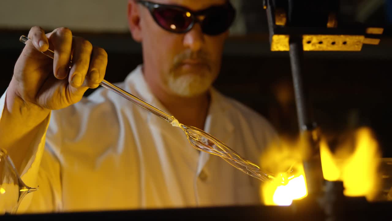 primer plano de un trabajador masculino maduro soplando vidrio en una fábrica de vidrio 4k
