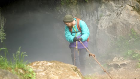 man rappelling down a foggy cave entrance