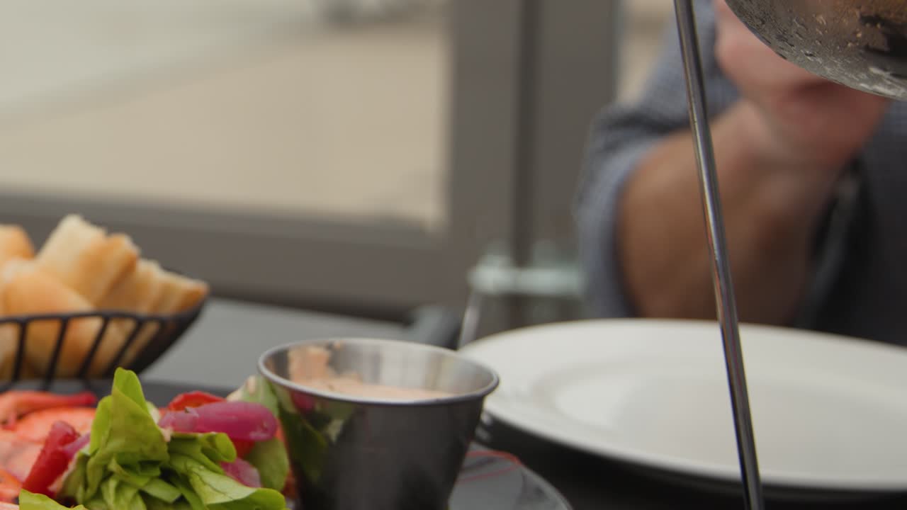 Man dining outdoors with seafood platter, white wine, natural daylight, relaxed coastal atmosphere, steady camera