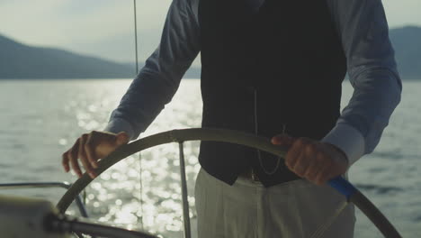 man steering a yacht at sunset