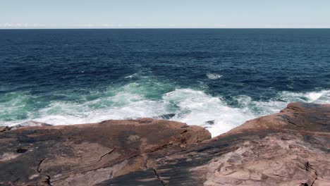 ocean waves crashing at the rocky waterfront at freshwater beach in australian state of new south wales