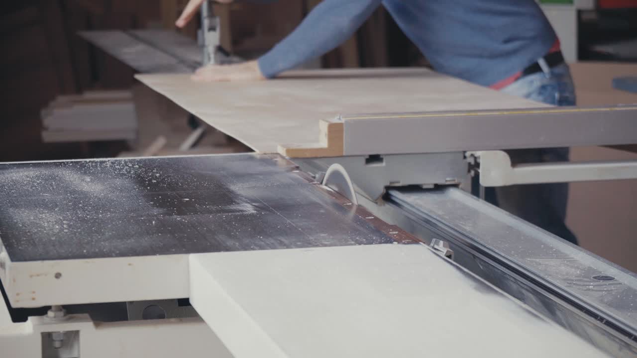 Carpenter cutting a sheet of plywood with table saw