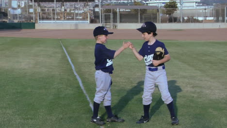 little league baseball players give each other playful handshakes