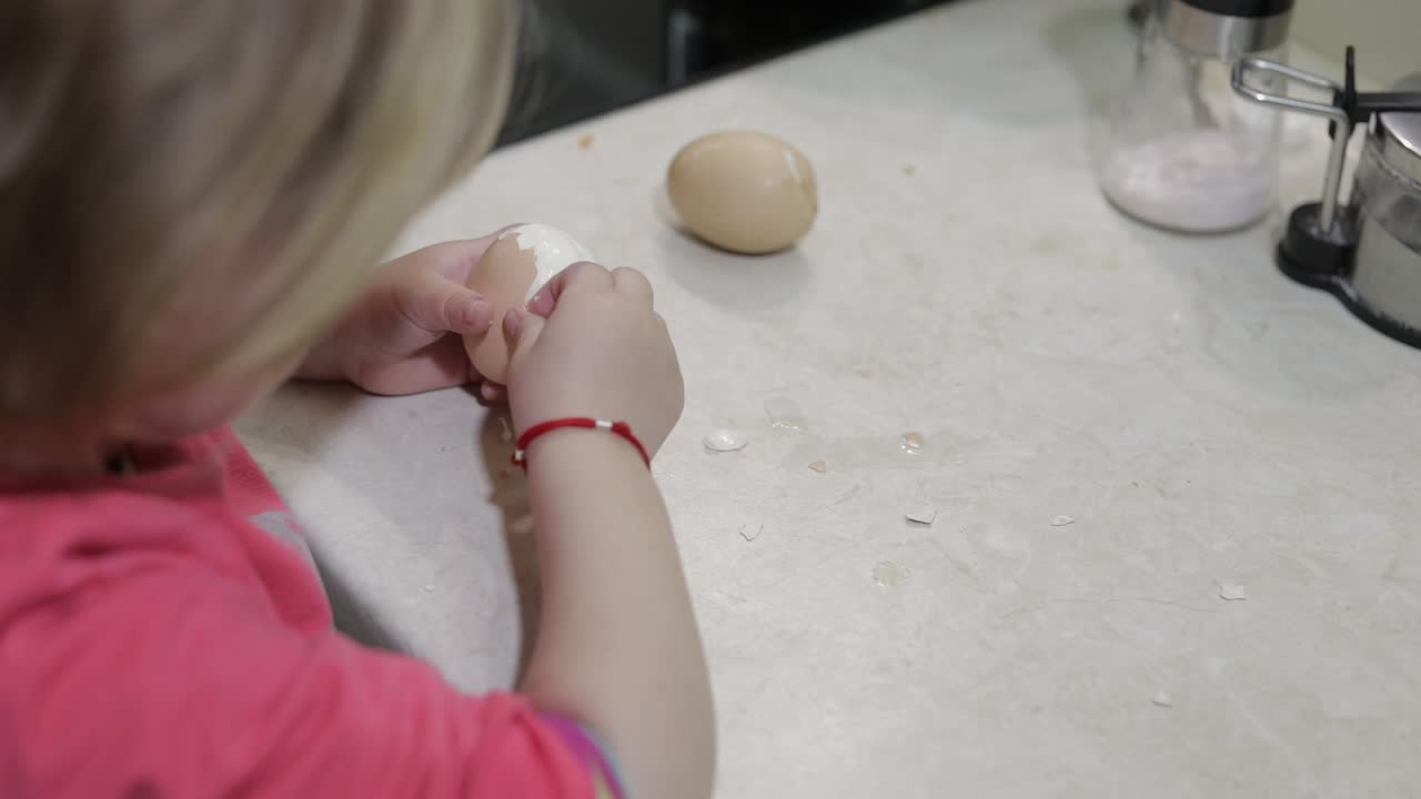 Closeup of a little girl cleans the shell with a boiled chicken egg