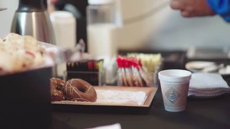 Persona-Agregando-Edulcorante-A-Su-Café-En-La-Mesa-De-Refrigerios