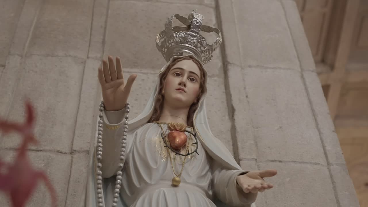Vista aproximada da estátua de Nossa Senhora de Fátima com coroa e rosário dentro de uma igreja portuguesa