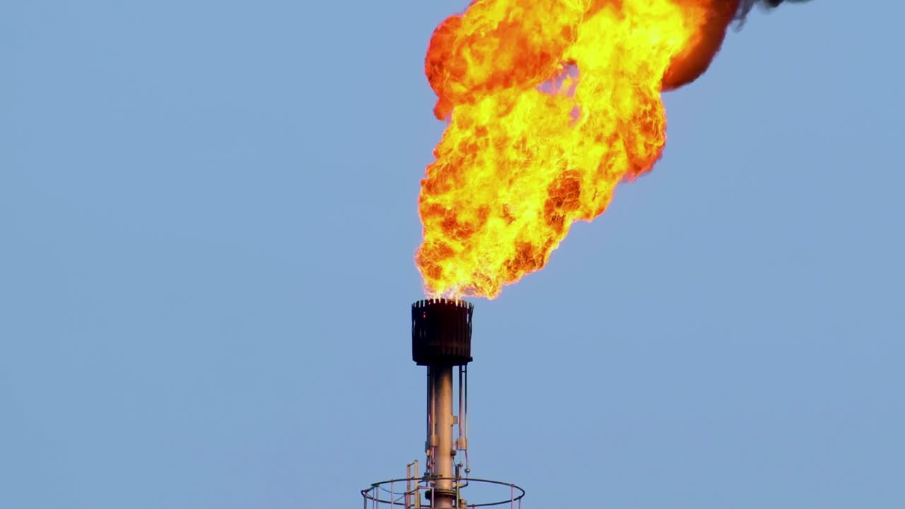 가까이서, 거대한 불꽃이 바람에 의해 불어오는 산업 굴 ⁇ 에서  ⁇ 아져 나옵니다.