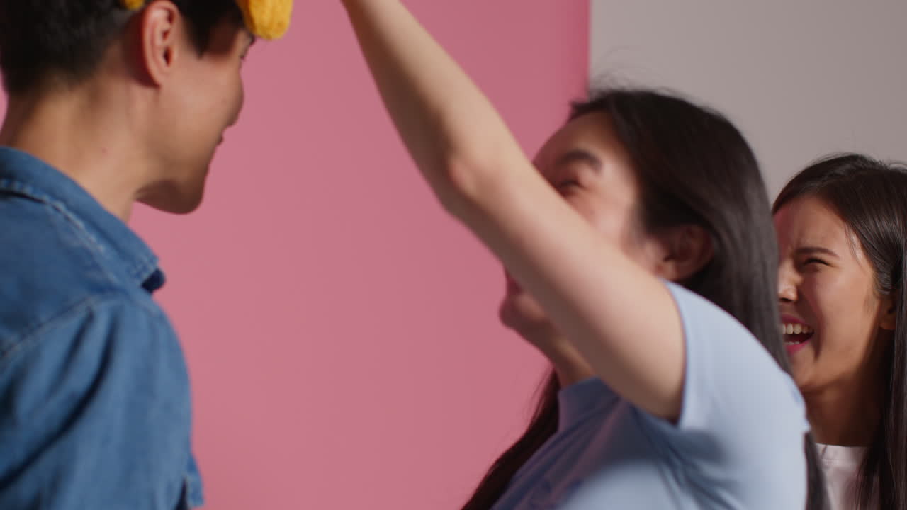 핑크색 스튜디오 배경 앞에 있는 젊은 친구 그룹이 프 4와 함께 사진 부스 스타일의 초상화를 위해 포즈를 취하고 있습니다.