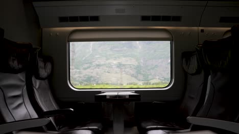 an empty business class train carriage with a scenic view of the swiss countryside passing by through the window, switzerland