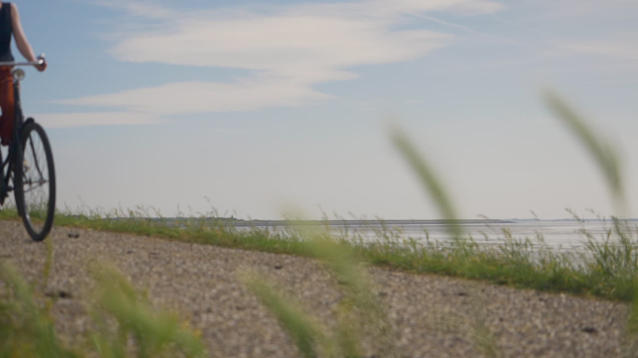 주황색 바지를 입은 여성 사이클리스트가 자전거를 타고 지나가는 슬로우 모션 샷